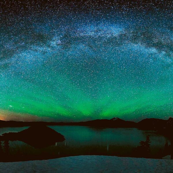 The Northern Lights (aurora borealis) stretching across a night sky with reflections over a still lake