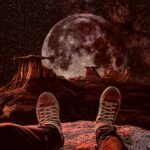 A spaceman sitting on a rocky terrain with a large moon looming in the background, perfect for an LED Box Frame display.