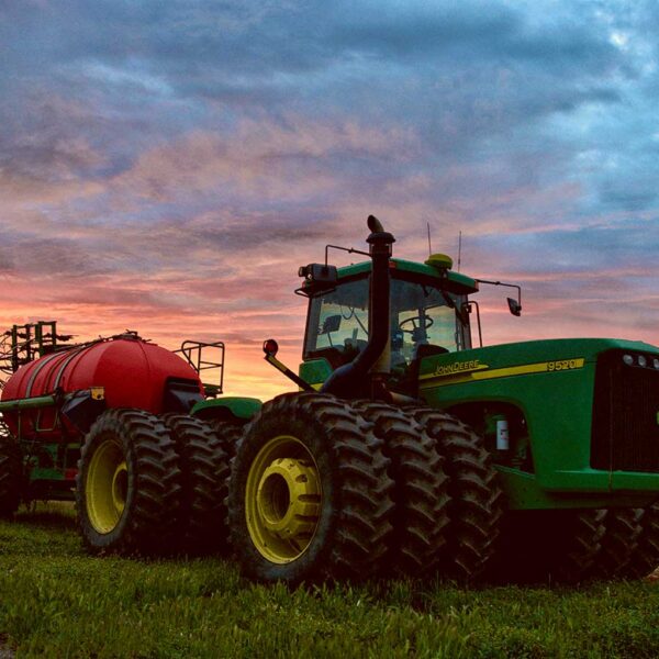 Green John Deere farm tractor in a field, perfect for display in an LED Box Frame for agricultural enthusiasts