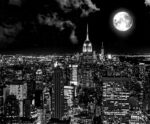 New York City skyline at night with a full moon glowing above the Empire State Building